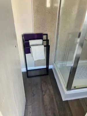 a towel rack next to a glass shower door at Bells yard Cottage Maryport in Maryport