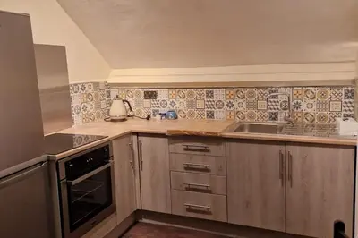 a kitchen with wooden cabinets and a sink and a stove at Eta's Manor @ Brooklands in Maryport
