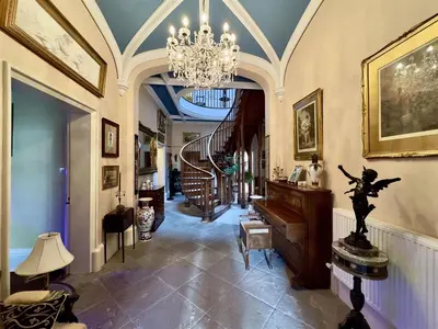 a living room with a chandelier and a staircase at Calthwaite Hall Bed & Breakfast in Penrith