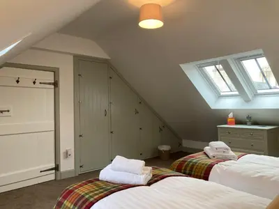 a attic bedroom with two beds and a window at Serendipity in Kirkcudbright