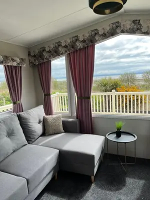 a living room with a couch and a large window at Marianne Bay - Southerness Caravan Park with Sea View - Pet Friendly in Mainsriddle