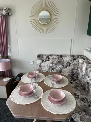 a table with plates and glasses and a mirror at Marianne Bay - Southerness Caravan Park with Sea View - Pet Friendly in Mainsriddle