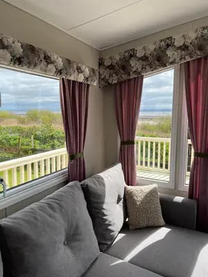 a living room with a couch and a large window at Marianne Bay - Southerness Caravan Park with Sea View - Pet Friendly in Mainsriddle