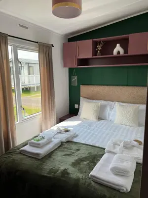 a bedroom with a large bed with towels on it at Marianne Bay - Southerness Caravan Park with Sea View - Pet Friendly in Mainsriddle