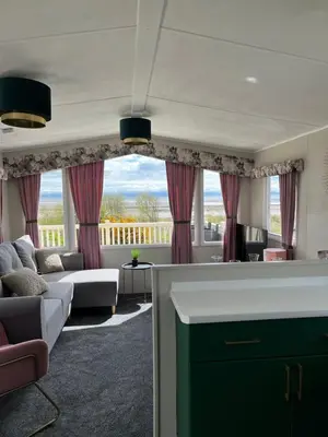a living room with a couch and a large window at Marianne Bay - Southerness Caravan Park with Sea View - Pet Friendly in Mainsriddle